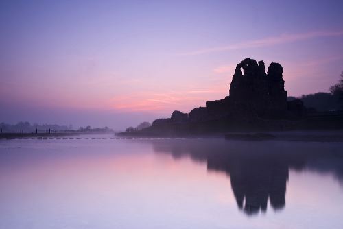 Sunrise over Ogmore Castle on a calm misty spring morning.